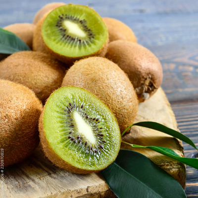 Einige frische Kiwis liegen ganz und halbiert liegen auf einem Holzbrett
